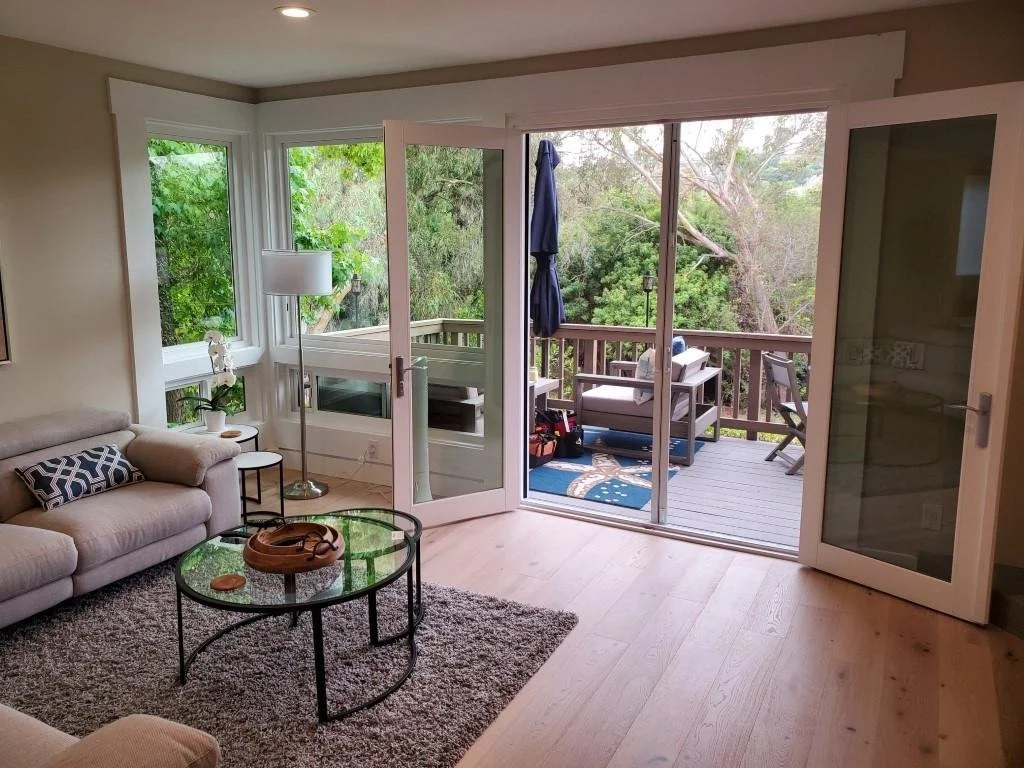 Screen doors connecting a furnished living room with an outdoor deck